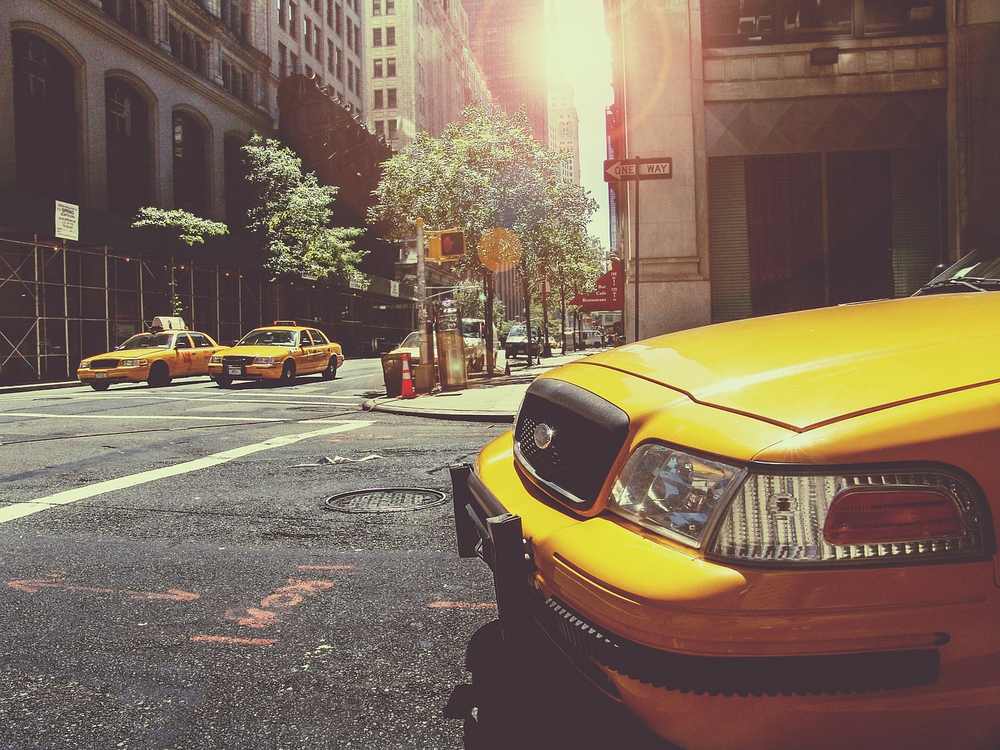 Deux taxis jaunes sur une rue de ville avec bâtiments et soleil Deux taxis jaunes sur une rue de ville avec bâtiments et soleil