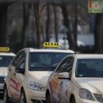 Des voitures-taxis alignées sur une rue, panneaux lumineux visibles