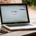 Un ordinateur portable affichant Google sur une table en bois, avec un smartphone