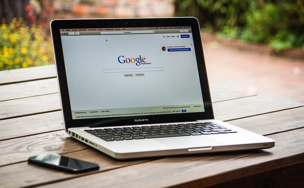 Un ordinateur portable affichant Google sur une table en bois, avec un smartphone