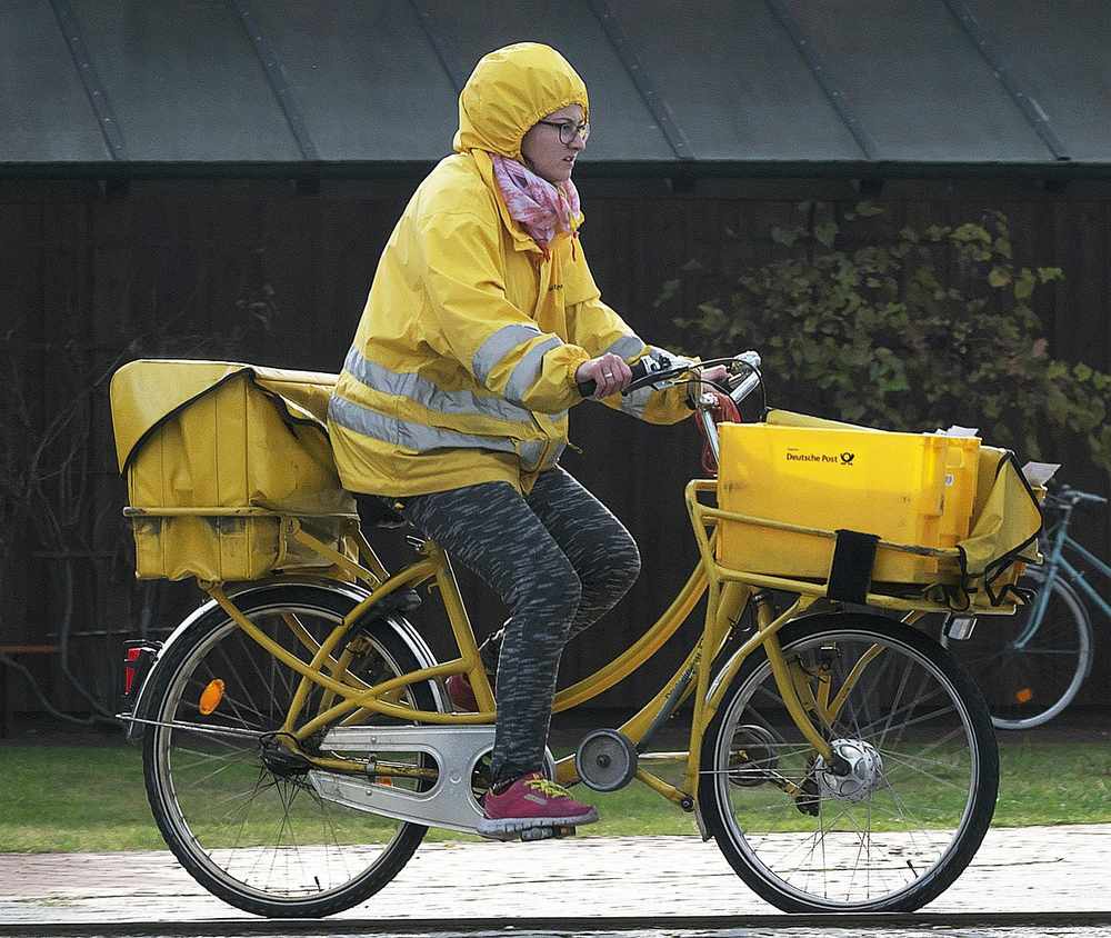 Une personne en tenue jaune conduit une bicyclette cargo chargée de caisses Une personne en tenue jaune conduit une bicyclette cargo chargée de caisses