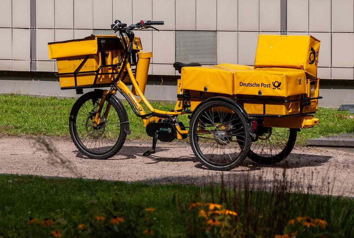 Vélo cargo jaune avec deux caisses, stationné près d'un bâtiment Vélo cargo jaune avec deux caisses, stationné près d'un bâtiment