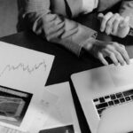 Une personne travaille sur un ordinateur portable, entourée de documents