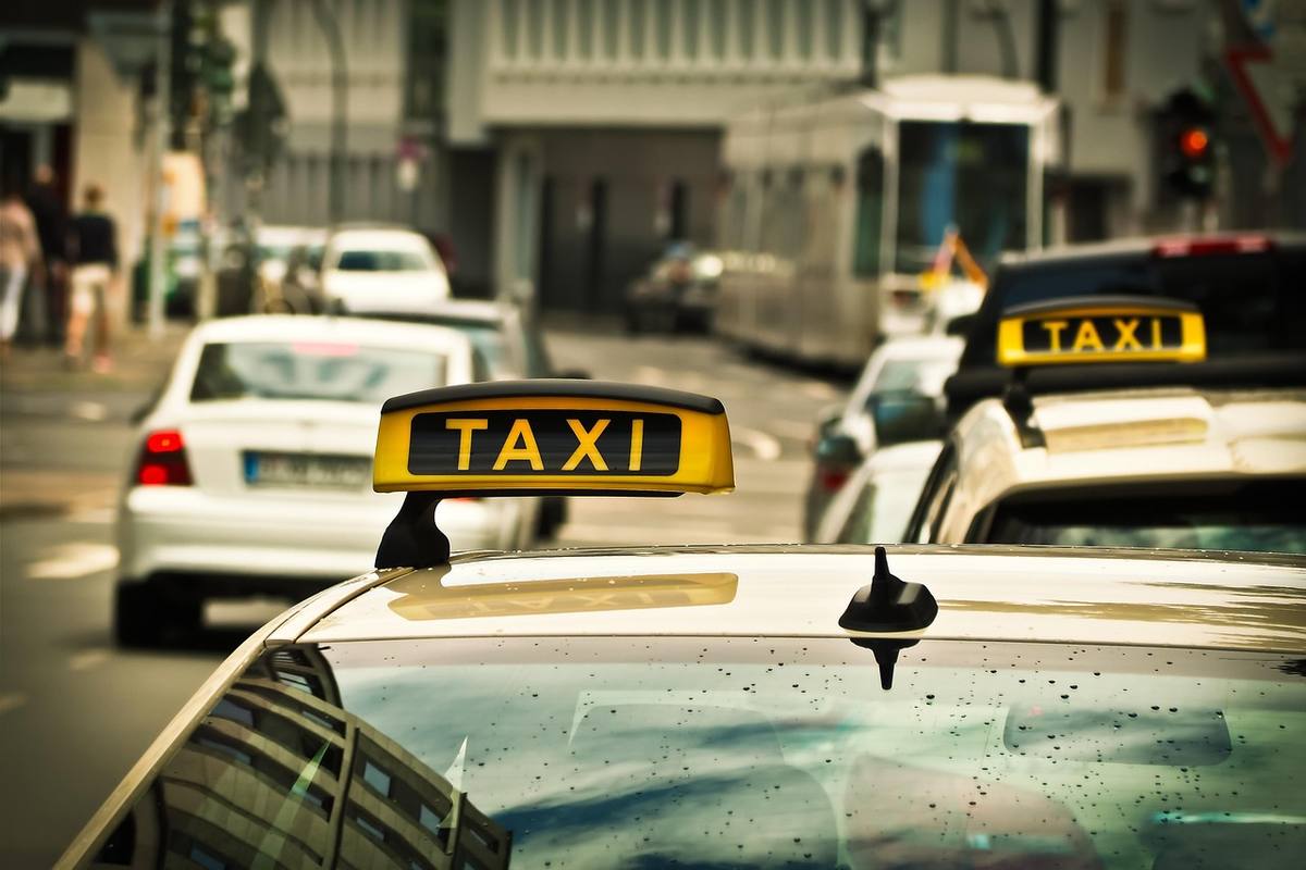 Des taxis jaunes avec panneaux 'TAXI' dans une rue urbaine animée Des taxis jaunes avec panneaux 'TAXI' dans une rue urbaine animée